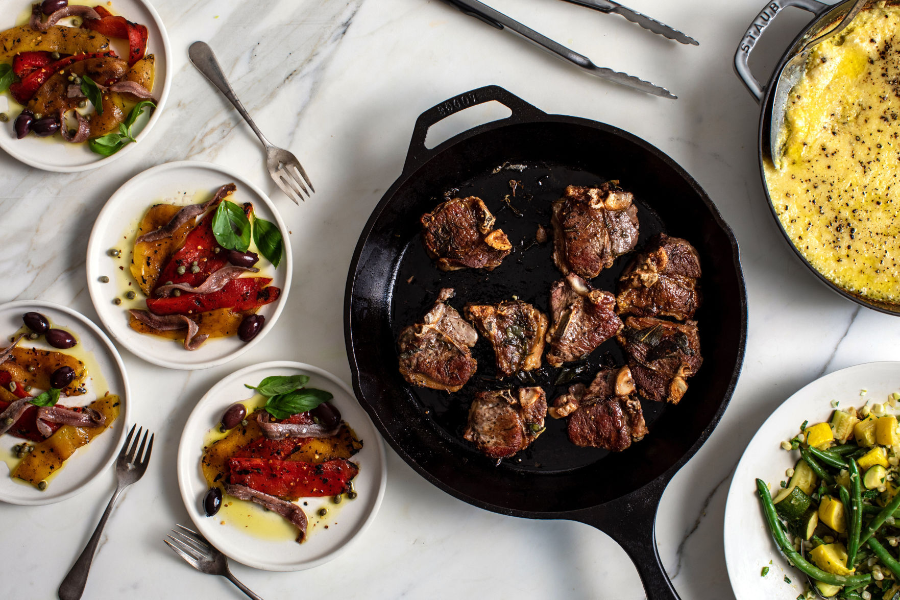 From left: roasted peppers with capers, olives and anchovies; pan-fried lamb chops; green beans with zucchini, corn and summer squash; baked polenta with ricotta and Parmesan, in New York, Aug. 29, 2020. (Andrew Scrivani/The New York Times)